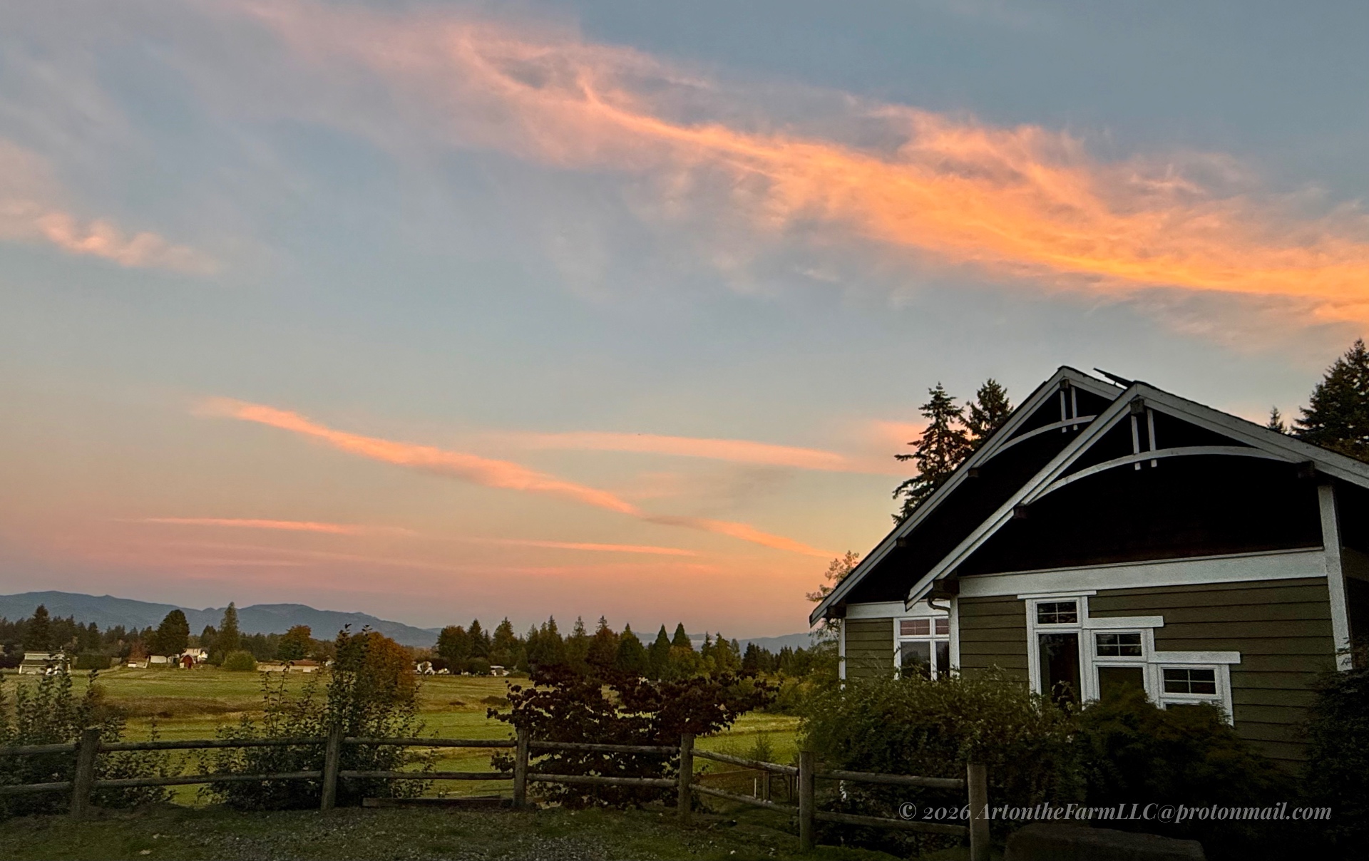 Pink and orange clouds above the green studio cottage and fields